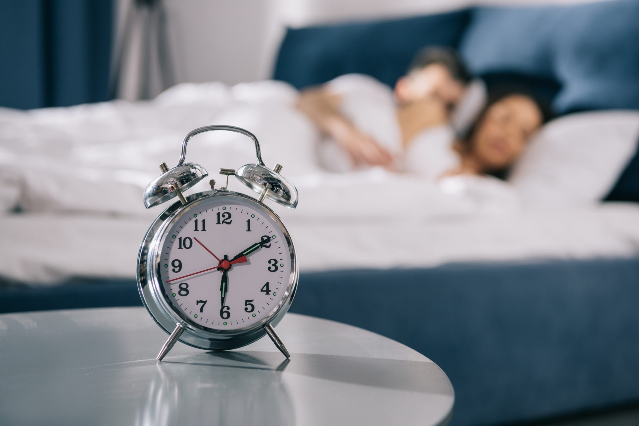 This picture shows a clock placed on tabal and a couple sleeping at the back; the context is about how to increase sex time